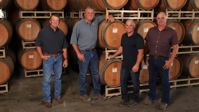 Lanza family, of Wooden Valley Winery, standing in front of wine barrels at Suisun Valley tasting room.